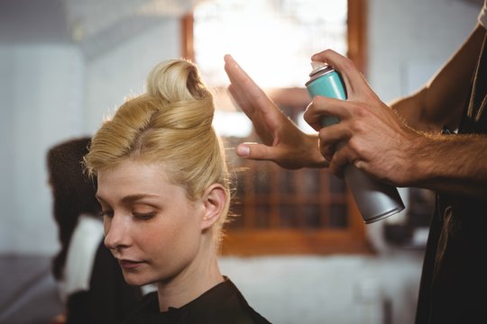 Hairdresser styling customers hair with spray