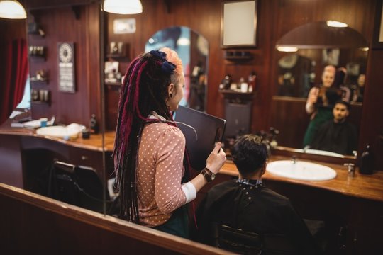 Female barber showing man his haircut in mirror