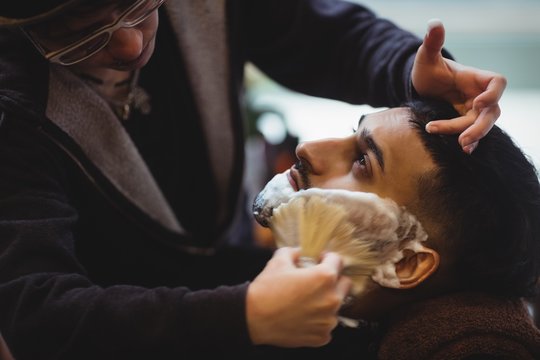 Man getting his beard shaved with shaving brush