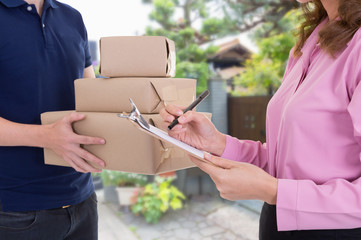 Woman signing receipt of delivery package at home.