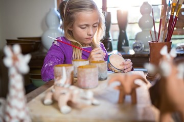 Attentive girl painting on bowl