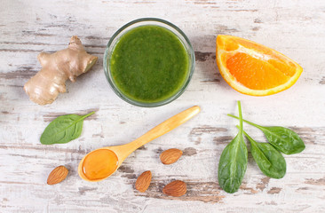 Ingredients and fresh cocktail from spinach on wooden background, healthy nutrition