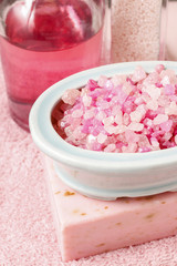 Bowl of pink sea salt, bar of handmade soap and bottle of liquid