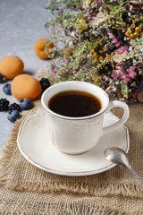 Cup of coffee and fresh fruits on jute background