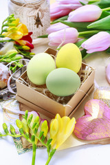 Easter decorations: colorful eggs in paper box, spring flowers a