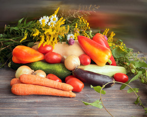 Summer crop concept - august fielf flowers and colorful vegetables on wooden kitchen table. 