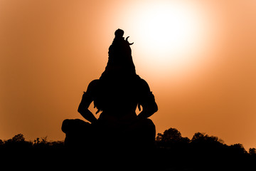 A silhouette of a statue of the Hindu god Shiva on the banks of the Ganges at Rishikesh in North...