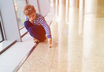 little boy playing with toy plane in the airport