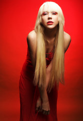 Perfect blond model in red dress over red background.