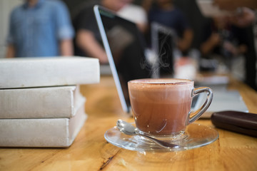 Cup of hot chocolate and text book.