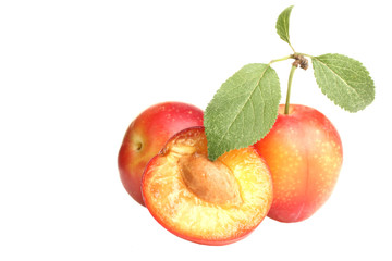red plums with leaves on white isolated background