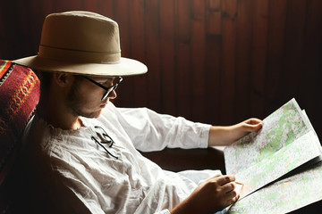 hipster man in glasses  looking at map and exploring, sitting on