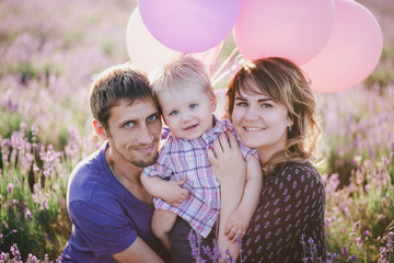 Happy family with colorful balloons posing in a lavender field. Summer mood