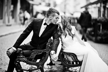 Wedding couple in love siting on bench at street of city