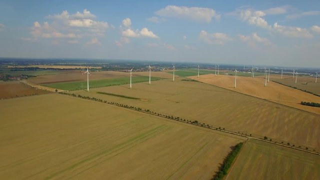 4K HD Wind turbine farm aerial video fly over ecological technologies power generating windmills produce clean renewable energy in countryside fields local road cars moving in distance Europe, Germany