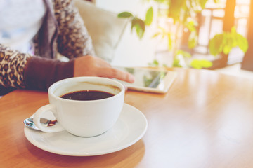 Asian woman using tablet computer in cafe drinking coffee.