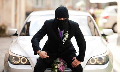 Groom in black mask sits on the grey BMW - obrazy, fototapety, plakaty