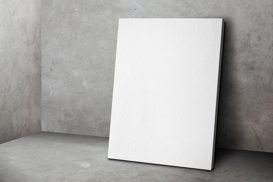 Blank white poster frame leaning at grunge grey concrete wall an