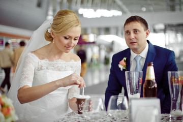 Elegant bride holds a cup of coffee sitting behind a groom