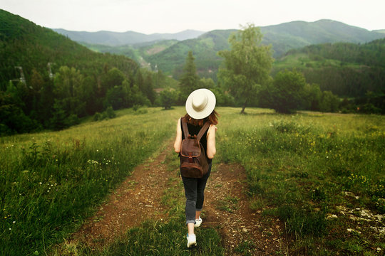 woman traveler with backpack and  hat walking in amazing mountai