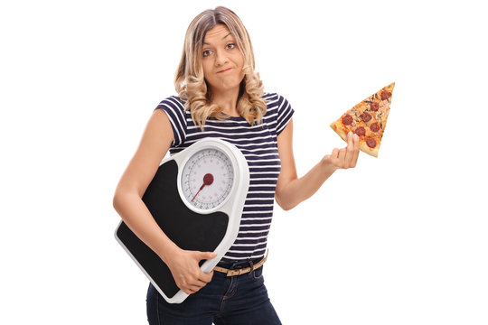 Woman holding slice of pizza and weight scale
