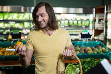 Man holding orange and basket of vegetables