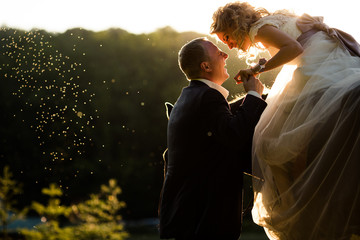 Groom laughs holding bride's hand while she rides a horse