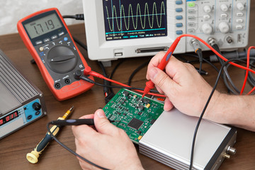 Engineer's hands with the probes testing voltage on the plate