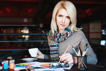 Fototapeta premium Girl sitting in cafe with cup of coffee and drawing