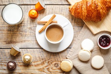 sweet breakfast with coffee, macaroons and croissants on wooden table