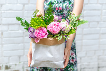 woman in dress with bouquet of peonies in kraft bag
