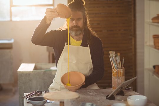 Male potter pouring watercolor in bowl - Powered by Adobe