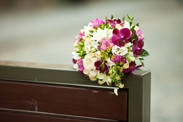 Brige and violet wedding bouquet lies on the back of a bench