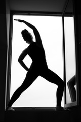 A silhouette of a woman doing yoga in window