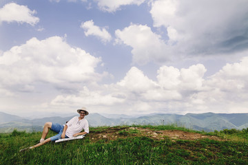 Naklejka na ściany i meble hipster traveler sitting at top of mountains with amazing view a
