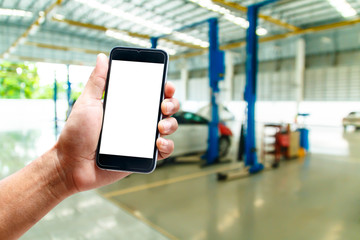 hand hold smartphone with car repair service center background blur