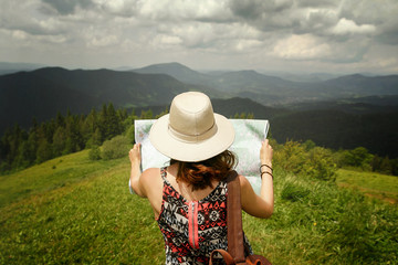 woman traveler holding map and looking at it exploring on top of