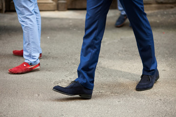 Man in blue trousers and blue shoes walks on the pavement