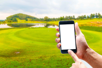 Hand using smartphone mobile in the vertical position, background blur of golf.