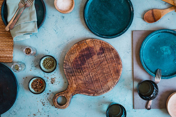 Dinner empty food table with turquoise ceramic plates and old wooden kitchen accessories.