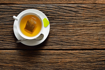 Top view of a cup of tea with tea bag on wooden table