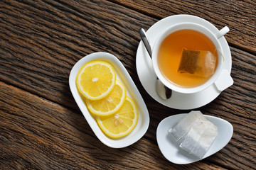Top view of cup of tea with tea bag, tea bags  lemon on wooden table