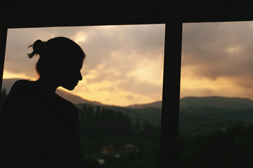 Fototapeta premium silhouette of hipster woman in wooden cottage window with view