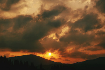 amazing sunset in mountains landscape, sun and clouds and woods