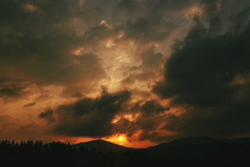 Naklejka na ściany i meble amazing sunset in mountains landscape, sun and clouds and woods