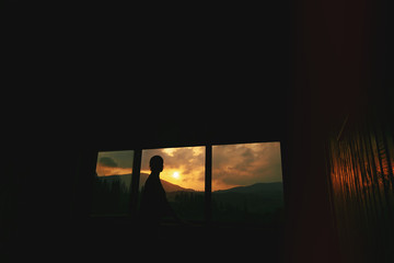 silhouette of woman in sunshine in wooden cottage window  with v