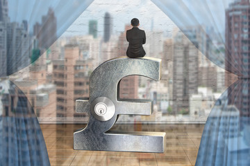 Businessman sitting on silver pound symbol with lock