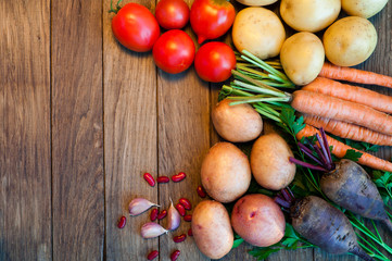 Tomatoes, potatoes, carrots, red beets on a wooden table