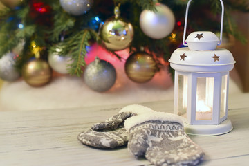 Christmas candle in the shape of a lantern with a candle inside.  In the background  Christmas tree decorated with toys and lights. Christmas spirit and decorate
