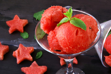 Watermelon balls in glass with mint and star of watermelon on a wooden table